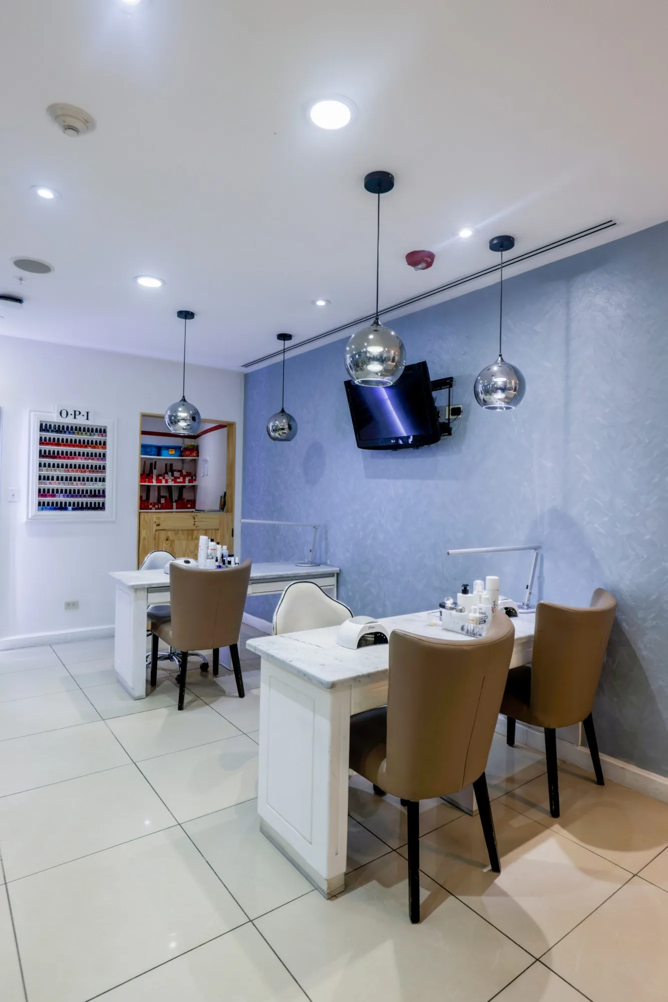 Mesas de manicure con pared texturizada y lámparas plateadas en Allure Belén